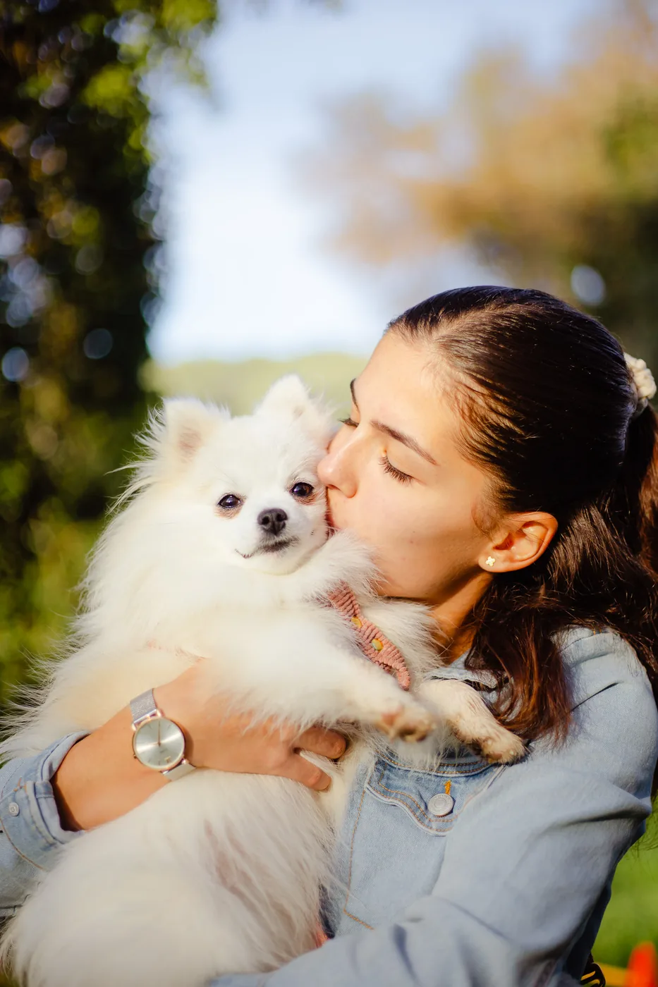 Jeune femme embrassant son chien blanc