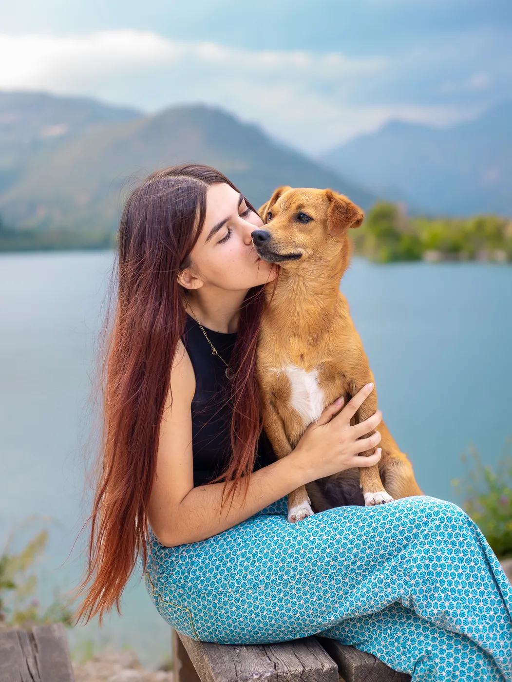 Jeune femme et son chien devant un lac de montagne